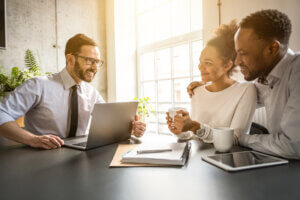 Black couple sitting with a man with glasses at a computer
