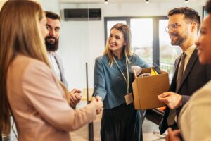 Woman shaking hands holding a box in an office